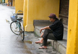 Old Vietnamese man sitting on curb