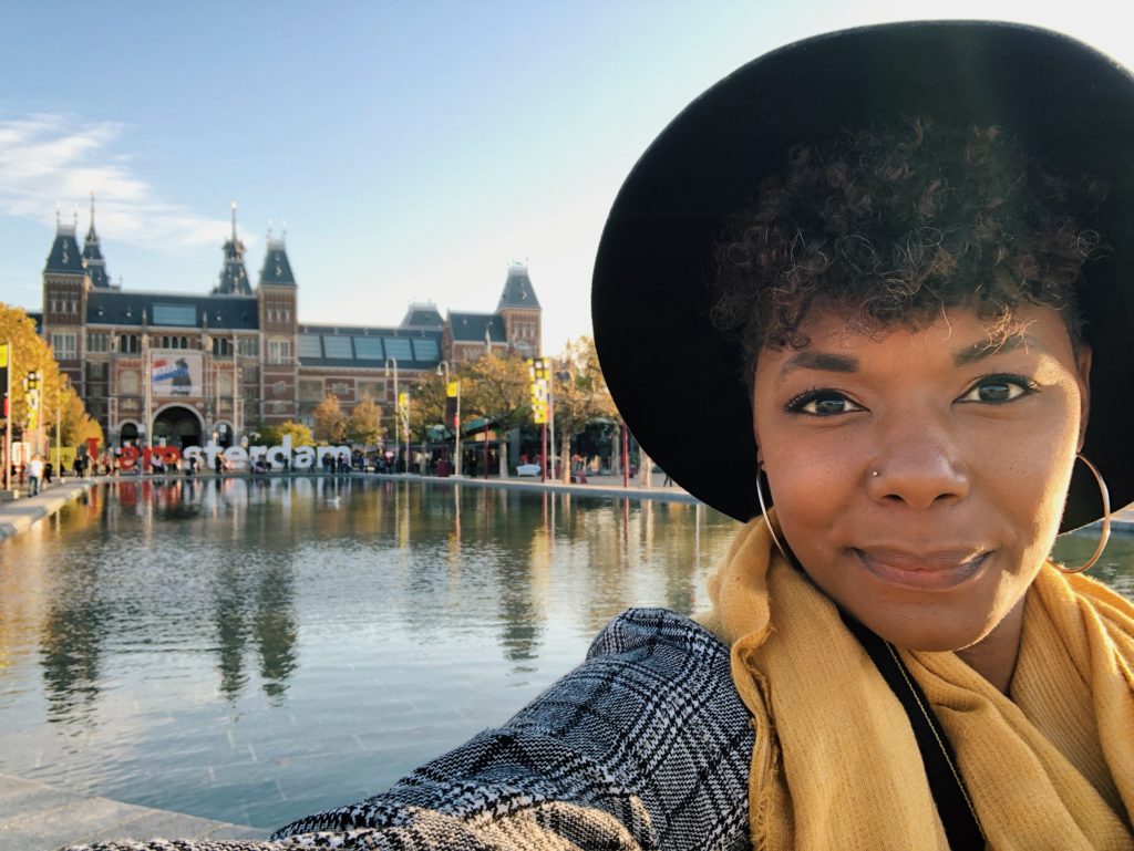 Black woman in front of I amsterdam sign in Amsterdam