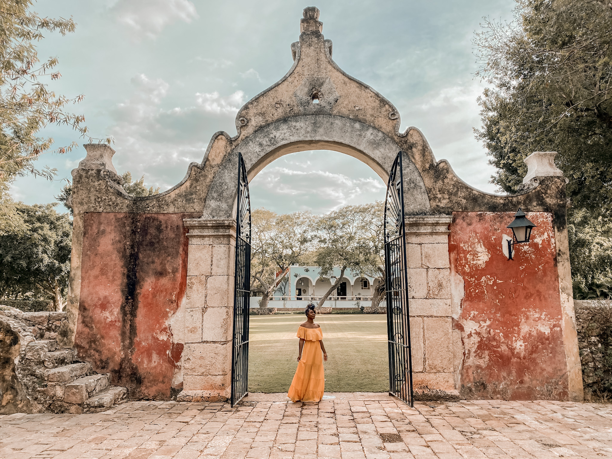 Black woman in a yellow dress in front of hacienda in Merida Mexico