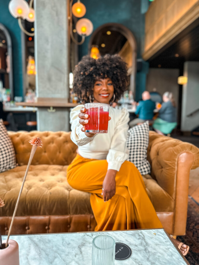 Black woman holding a cocktail at luxury boutique hotel in Denver, Colorado