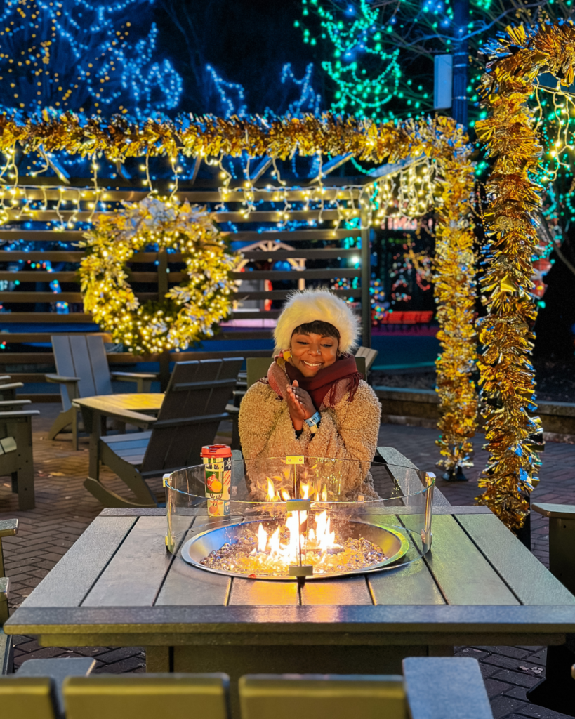 Black woman sitting in front of fire pit with fest Christmas decor in the background